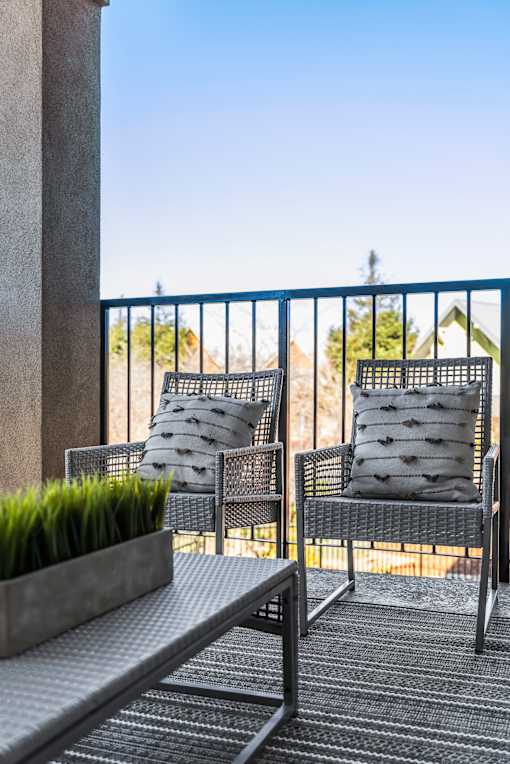 Two chairs and a table on a balcony.