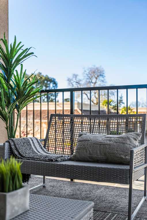 A black metal patio set with a grey cushion and a grey throw on it.