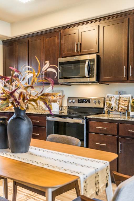 A kitchen with brown cabinets and a wooden table.