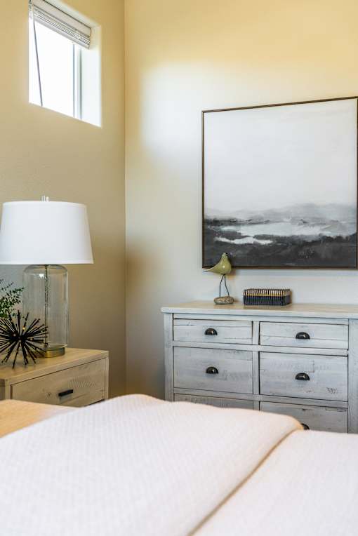 A bedroom with a bed, nightstand, and a large picture on the wall.
