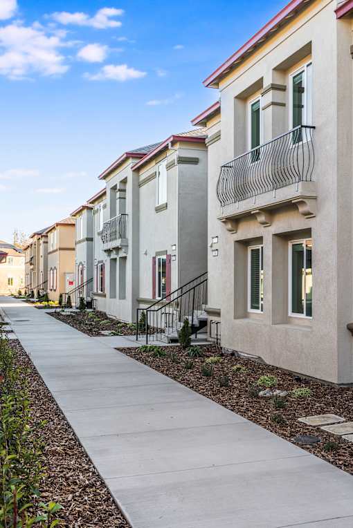 A row of houses with a concrete walkway in between.