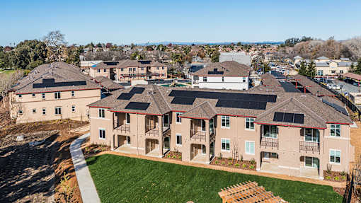 A large building with a lot of windows and a green lawn in front.