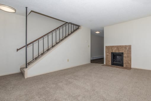 an empty living room with a staircase and a fireplace