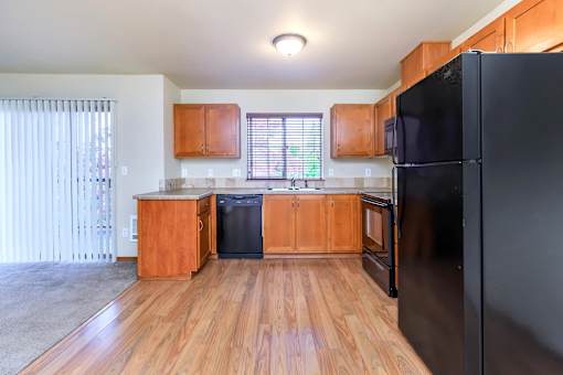 Open kitchen with wood cabinets and black appliances at Monroe Avenue Apartments, Salem, OR 97301