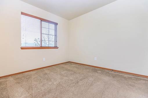 Empty carpeted bedroom with window and blinds at Monroe Avenue Apartments, Salem, OR