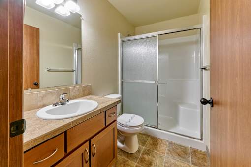 Guest bathroom with tiled flooring and glass shower door at Monroe Avenue Apartments, Oregon