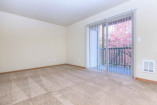 Empty carpeted living room with patio door at Monroe Avenue Apartments, Salem