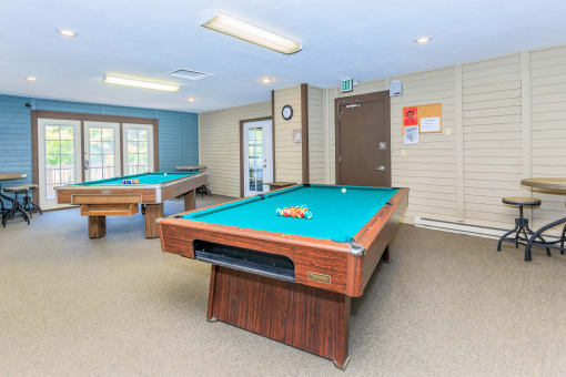 a game room with two pool tables and two billiards