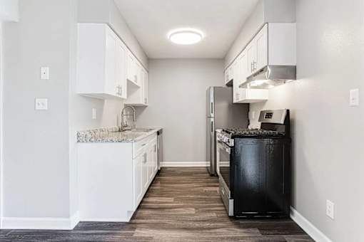 A kitchen with white cabinets and a black trash can at Chelsea Place Apartments, Georgia, 30058