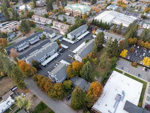 An aerial view of a parking lot and buildings surrounded by trees. at Ironwood Apartments, Coeur dAlene