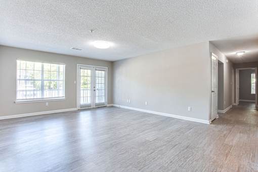 A spacious room with wood flooring and a large window at Ballantyne Commons of Stockbridge Apartments, Georgia, 30281