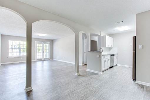 A spacious living room with a kitchen area in the background at Ballantyne Commons of Stockbridge Apartments, GA, 30281