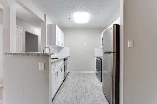 A kitchen with a refrigerator, cabinets, and a counter at Ballantyne Commons of Stockbridge Apartments, Georgia, 30281