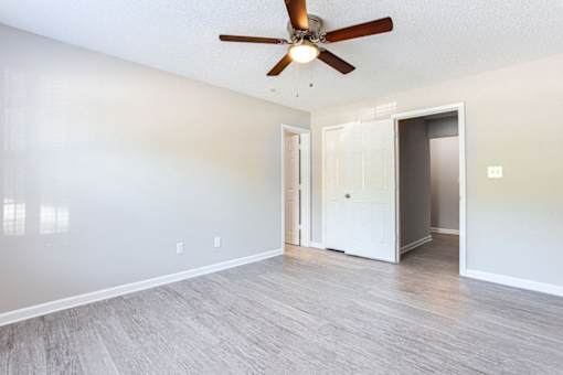 A room with a ceiling fan and light fixture, two doors, and a wall-mounted light switch at Ballantyne Commons of Stockbridge Apartments, Stockbridge, Georgia
