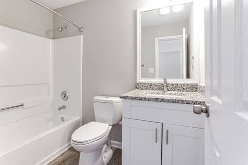 A white bathroom with a toilet, sink, and bathtub at Ballantyne Commons of Stockbridge Apartments, Stockbridge