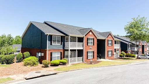 A row of townhouses with a clear blue sky above at Ballantyne Commons of Stockbridge Apartments, Georgia