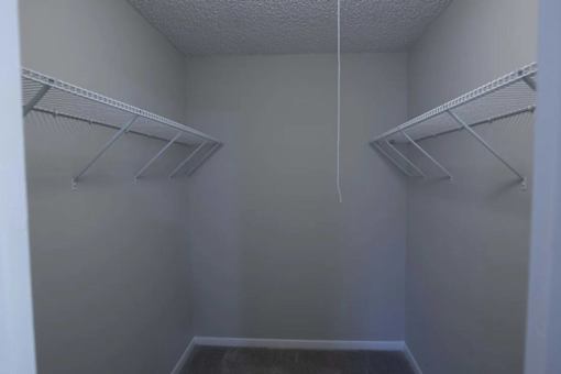 Empty walk-in closet with white shelves and a white ceiling at The Madison Apartments and Townhomes, Lawrenceville, GA, 30044