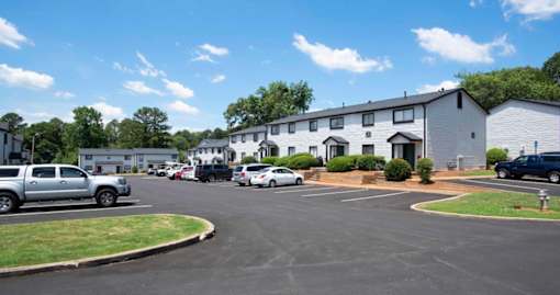 A parking lot with cars and a building in the background at The Madison Apartments and Townhomes, Lawrenceville, GA