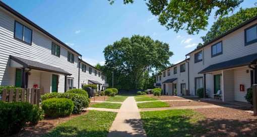 A row of houses with a pathway in the middle at The Madison Apartments and Townhomes, Georgia 30044