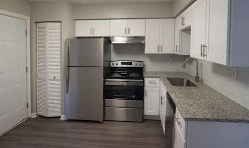 A kitchen with a refrigerator, oven, and sink at The Madison Apartments and Townhomes, Lawrenceville, GA, 30044