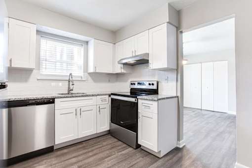 A kitchen with white cabinets and a black countertop at Barcelo at East Cobb Apartments, Georgia, 30067