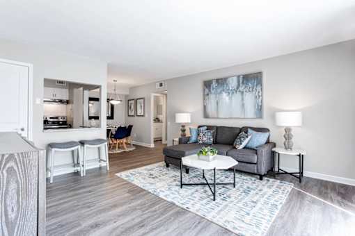 A living room with a grey couch, a white coffee table, and a painting on the wall at Barcelo at East Cobb Apartments, Marietta