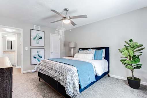 A bedroom with a bed, a ceiling fan, and a plant at Barcelo at East Cobb Apartments, GA, 30067