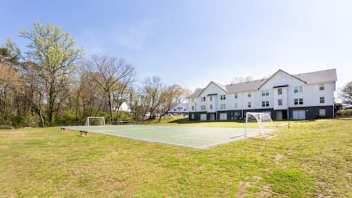 A tennis court is located in front of a white building at Barcelo at East Cobb Apartments, Georgia
