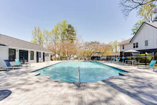 A large outdoor swimming pool surrounded by a tiled patio and lounge chairs at Barcelo at East Cobb Apartments, Marietta, GA, 30067