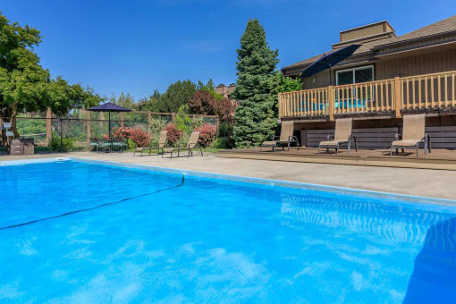 a pool with a deck and a house in the background