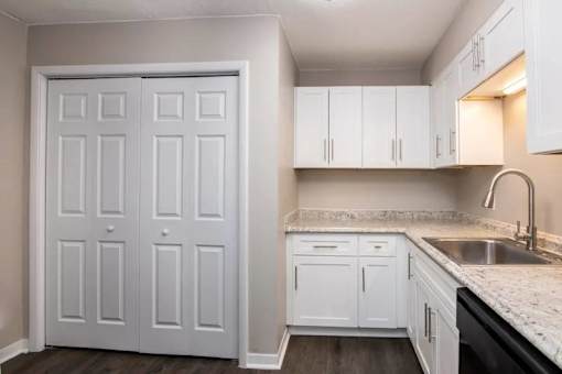 a white kitchen with white cabinets and a sink at Cleo Apartments, Alabama, 35611