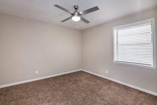 an empty bedroom with a ceiling fan and a window at Cleo Apartments, Athens, 35611