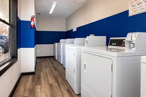 a row of washers and dryers in a room with blue and white walls at Cleo Apartments, Athens, 35611