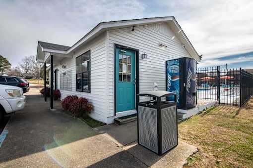 a small white building with a blue door and a trash can at Cleo Apartments, Alabama, 35611