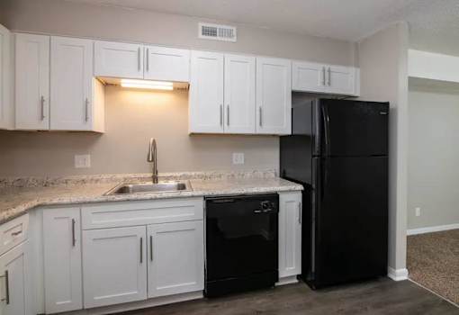a kitchen with white cabinets and black appliances at Cleo Apartments, Athens, AL