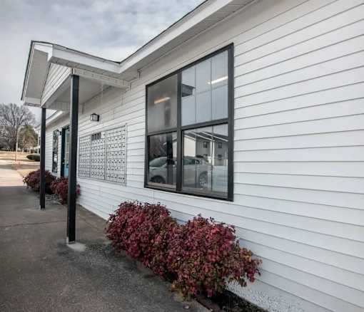 the side of a white building with windows and a sidewalk at Cleo Apartments, Athens, AL