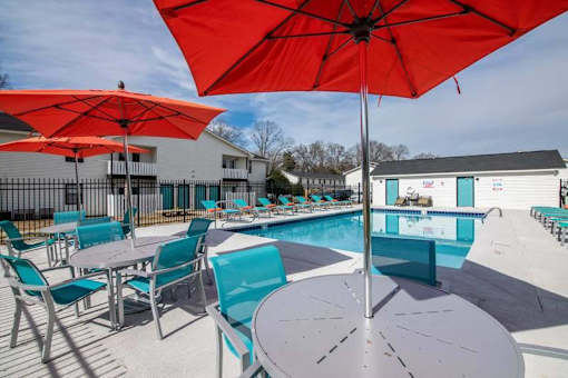 a pool with chairs and umbrellas around it at Cleo Apartments, Athens, Alabama