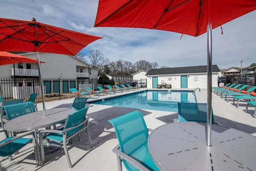 a swimming pool with tables and chairs and umbrellas at Cleo Apartments, Alabama, 35611