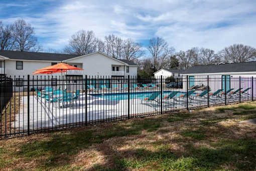 a pool with a fence in front of a house at Cleo Apartments, Athens, AL