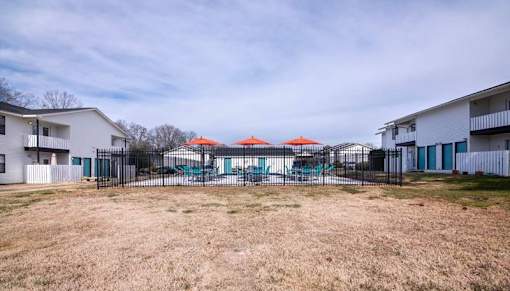 a yard with a fenced in pool and some houses at Cleo Apartments, Athens, Alabama