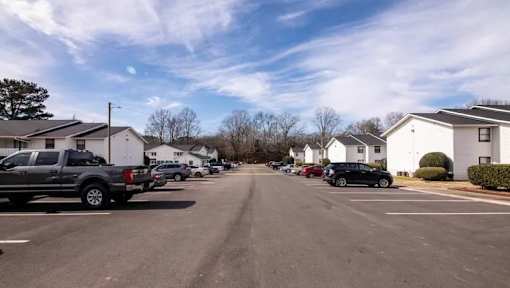 a city street with cars parked in a parking lot at Cleo Apartments, Alabama, 35611