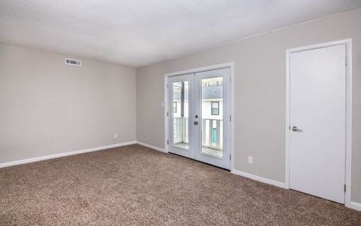 an empty living room with white walls and white doors at Cleo Apartments, Athens, AL