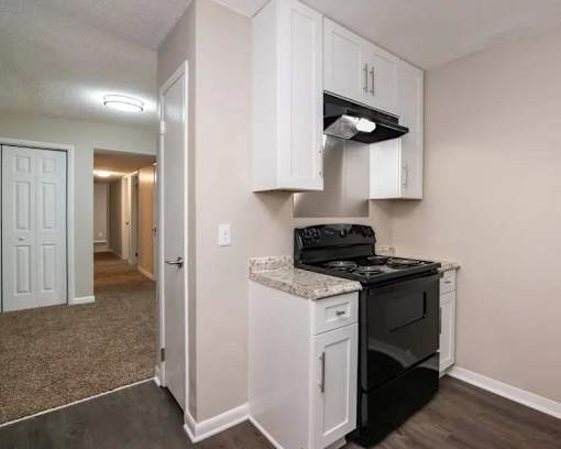 a kitchen with white cabinets and a black stove at Cleo Apartments, Athens, 35611