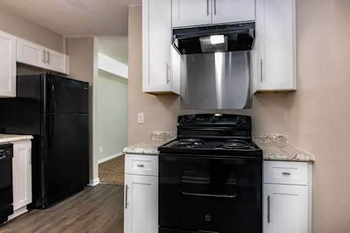 a kitchen with black appliances and white cabinets at Cleo Apartments, Alabama, 35611
