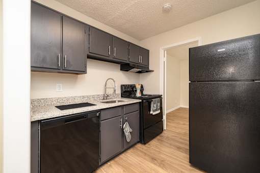 A kitchen with black cabinets and appliances at Overlook Club Apartments, Cummings, 30040