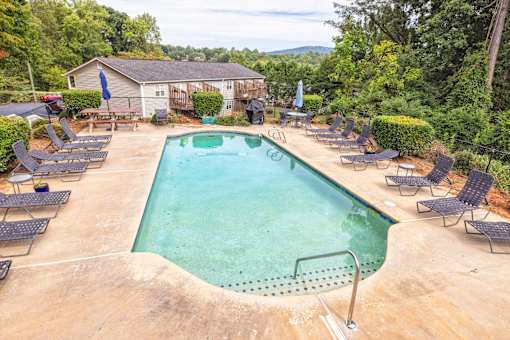 A large outdoor swimming pool surrounded by lounge chairs at Overlook Club Apartments, Cummings, Georgia
