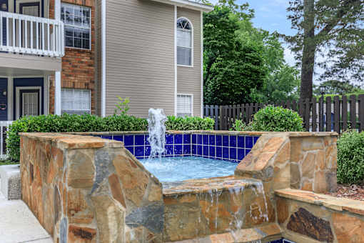 a pool with a fountain in front of a house at The Davis Apartments, Alabama  