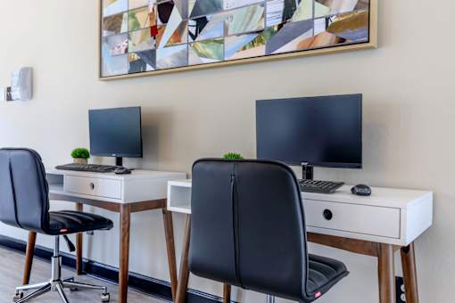 two desks with two monitors and two chairs in a room at The Davis Apartments, Alabama, 35816