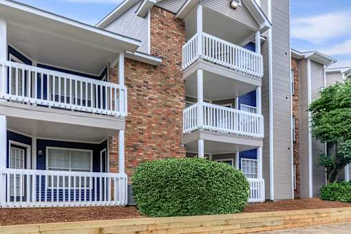 a building with two balconies and a bush in front of it at The Davis Apartments, Huntsville, AL 35816  
