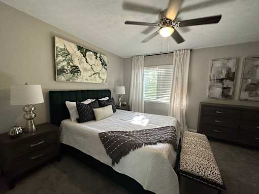 A bedroom with a bed, nightstand, and a ceiling fan.